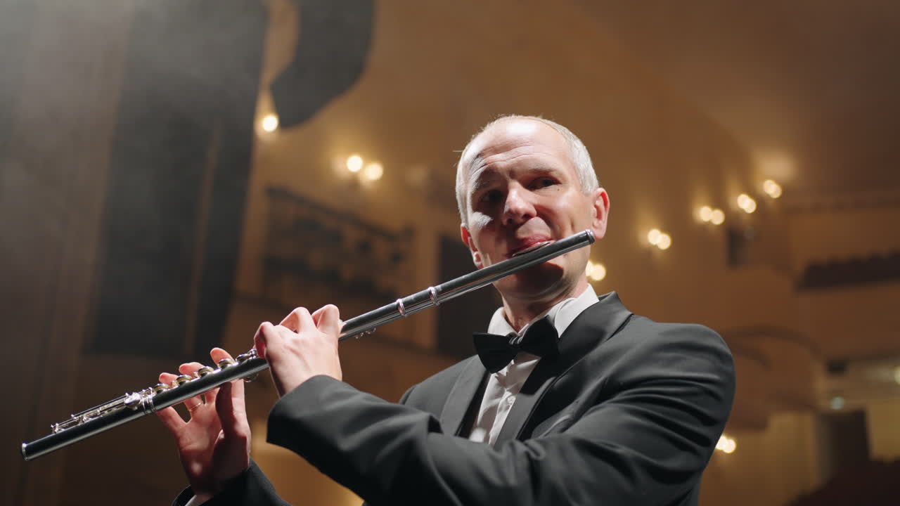현대 뮤직홀에서 연주하는 플루트 연주자 무대에서 플루트를 들고 있는 음악가의 초상화 클래식 음악 콘서트