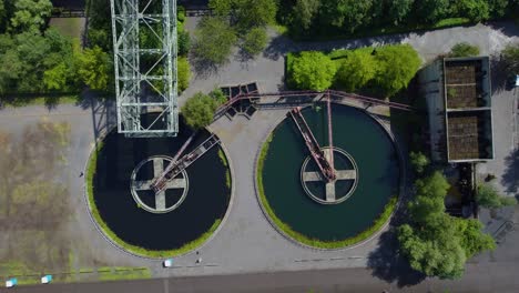 large industrial area with two widely spread gigantic circles in the middle with a stone crosses and metal rusty cranes coming out in the middle of nowhere abandoned place power plant surrounding park