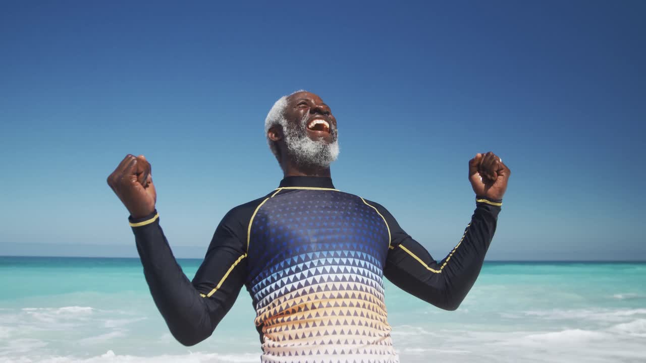 Senior man raising his arms at the beach