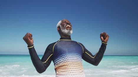 senior man raising his arms at the beach