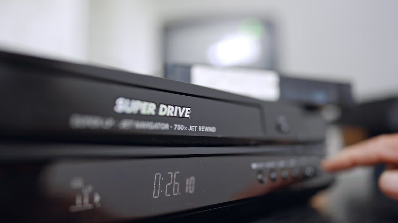 Pannello frontale del vecchio videoregistratore VHS. Primo piano. Una mano preme il pulsante sul registratore. Sfondo sfocato