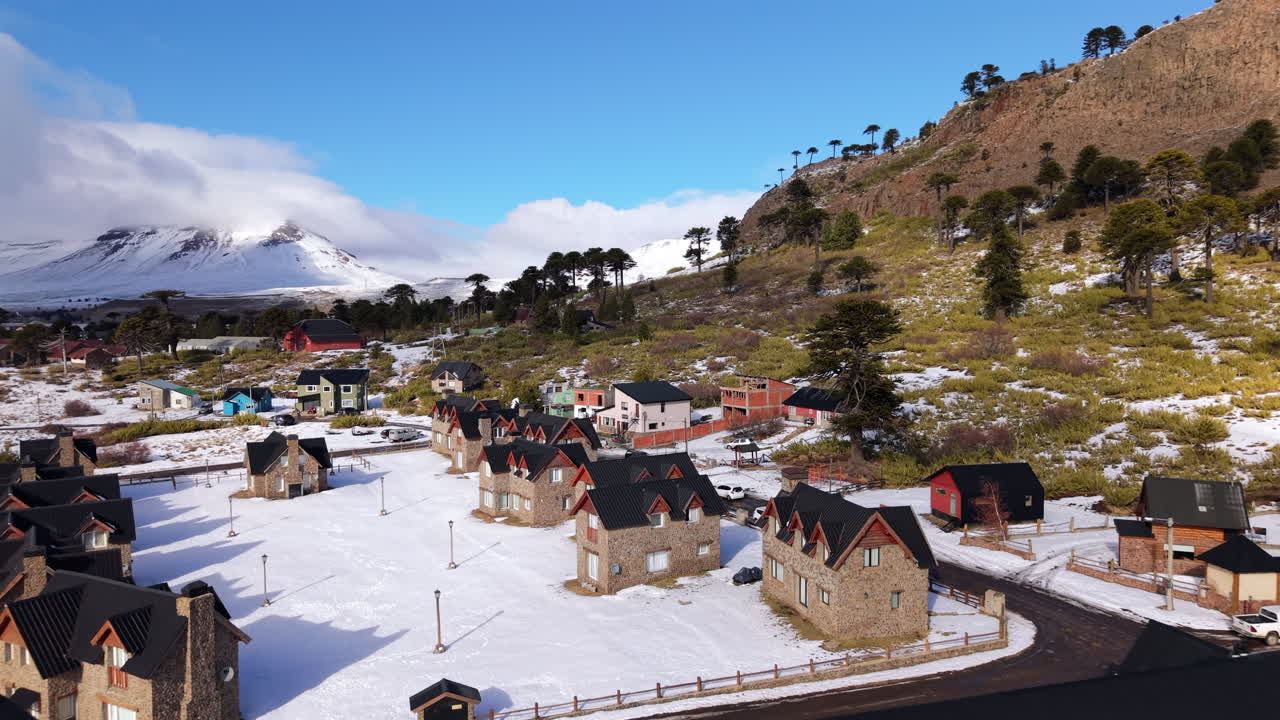 Aerial fly over snowy Caviahue village houses surrounded by hills and mountains, Caviahue-Copahue, Neuquén, Argentina