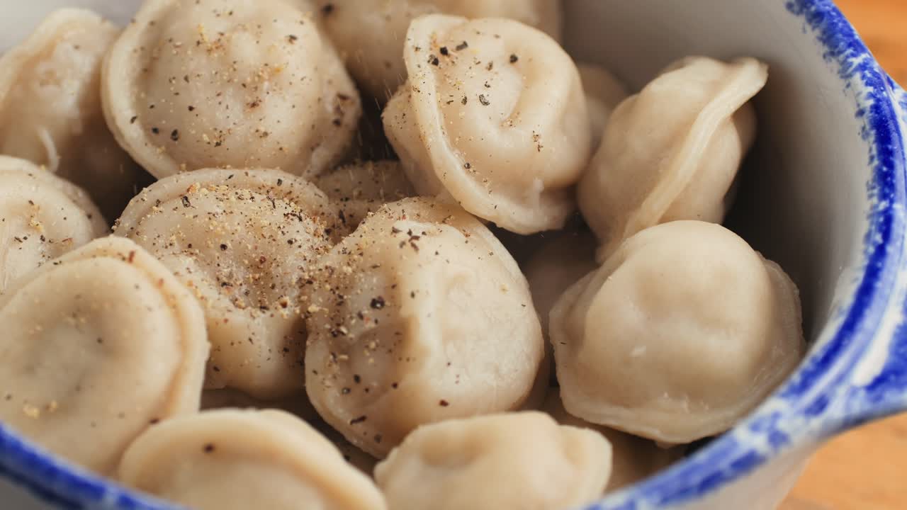 A bowl of pelmeni dumplings with pepper