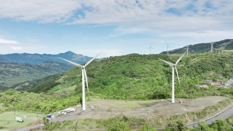 majestic aerial footage of elongated wind turbines atop rolling hills