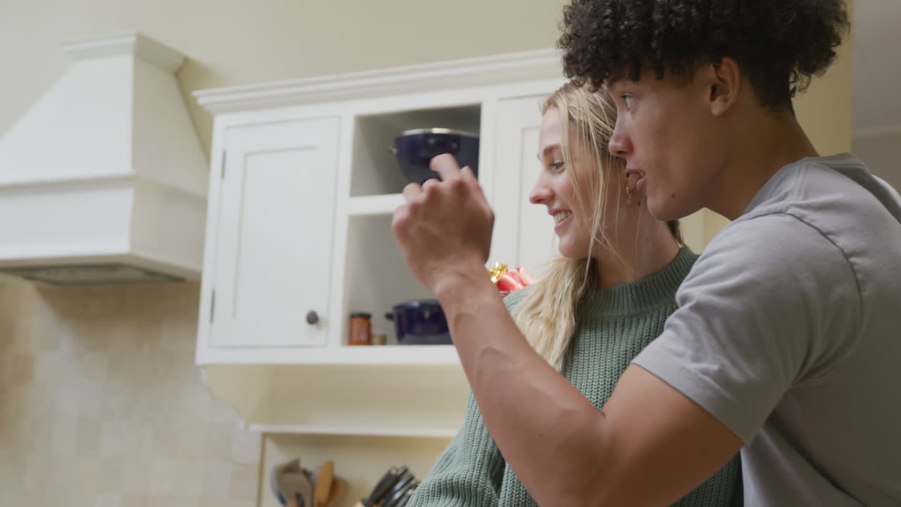 Happy diverse couple embracing and giving gift at home
