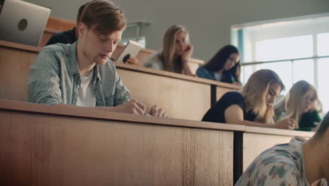 the camera moves through the audience where the students write a lecture on laptops and notebooks for professors in a large classroom of a university or college.