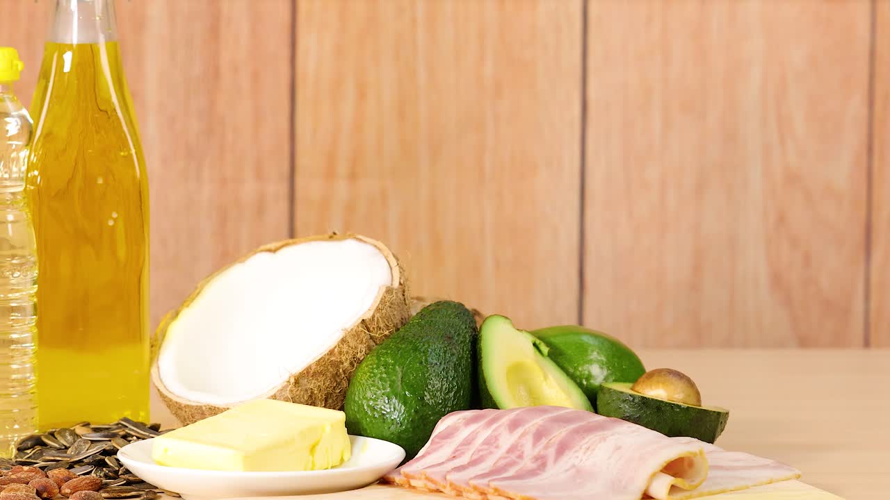 A variety of healthy fats and oils arranged on a wooden surface with natural lighting