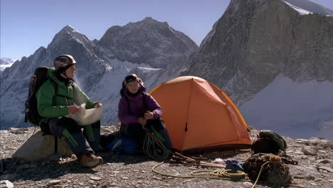 two mountaineers resting at a high-altitude camp amidst snow-capped mountains