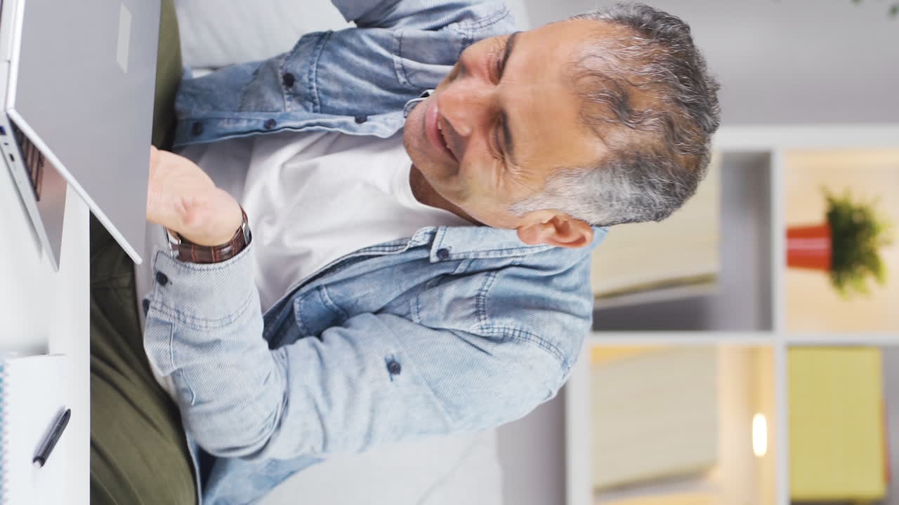 video vertical de un hombre abrazando alegremente la computadora portátil.