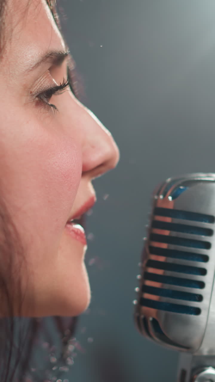 여성 가수가 열정적으로 빈티지 마이크로 노래하는 강렬한 클로즈업, 초점을 강조하는 흐릿한 배경
