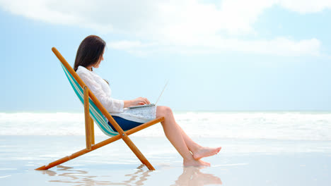 Side-view-of-young-caucasian-woman-using-digital-tablet-at-beach-4k