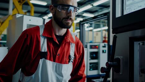 skilled factory worker in uniform and safety glasses carefully operates a machine, monitoring its performance on a digital display in a bustling industrial setting