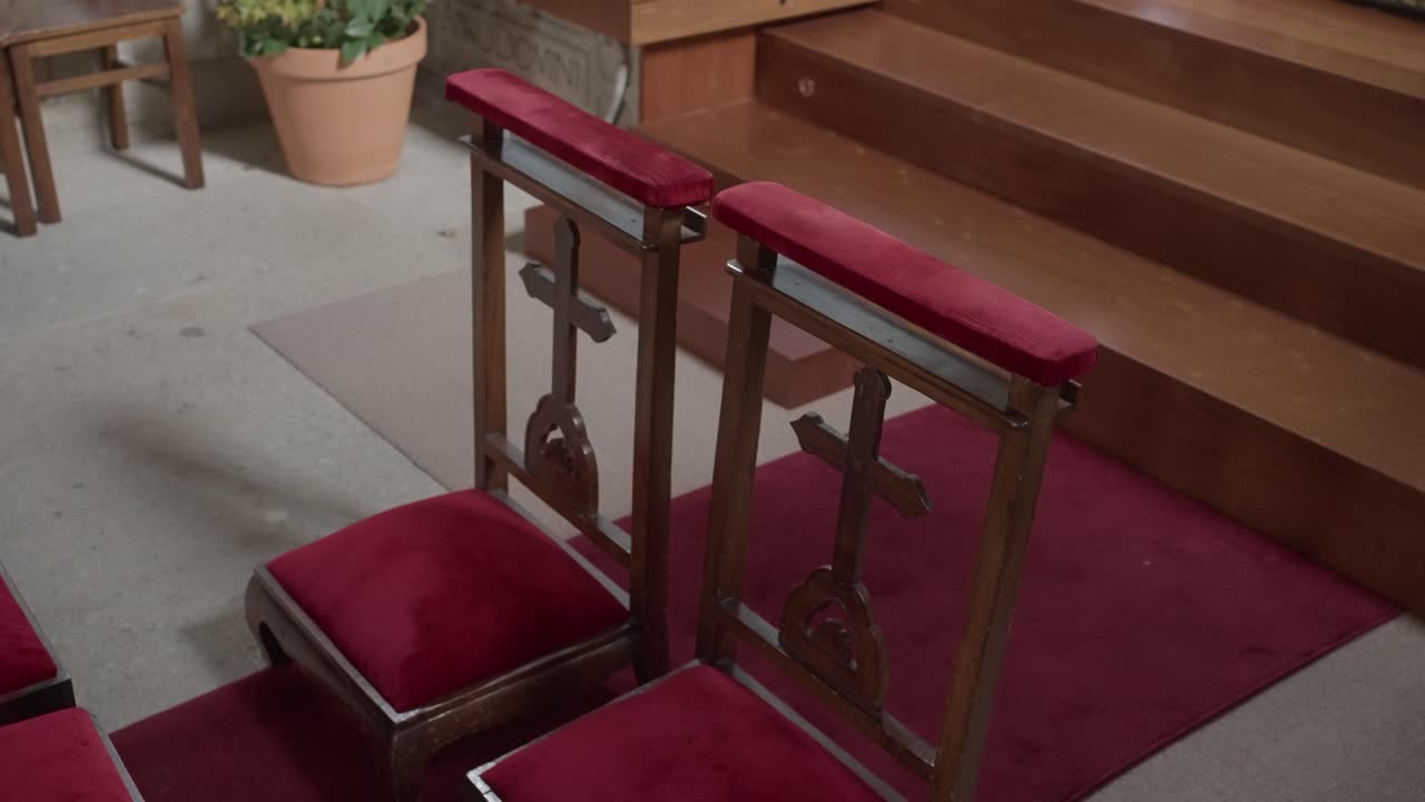 제단 앞에 빨간 벨벳 쿠션과 조각된 십자가가 있는 나무 기도 받침대