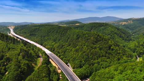 Scenic road through green hills. A highway stretches through verdant hills under a clear blue sky, showcasing a serene countryside landscape