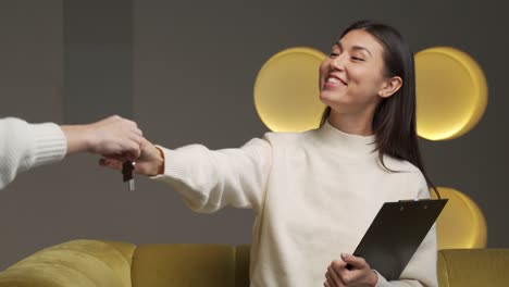 the real estate agent hands over the keys to the house to a young woman