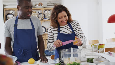 male and female adult students preparing ingredients for dish in kitchen cookery class