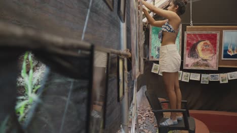 Slow-motion-shot-of-an-Indian-woman-meticulously-hangs-her-artwork-at-an-art-gallery