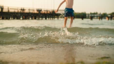 boy is running and jumping into sunny summer lake