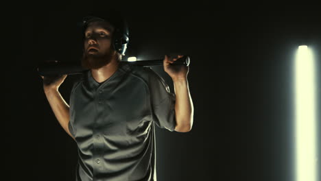 jugador de béisbol profesional caucásico posando contra un fondo oscuro