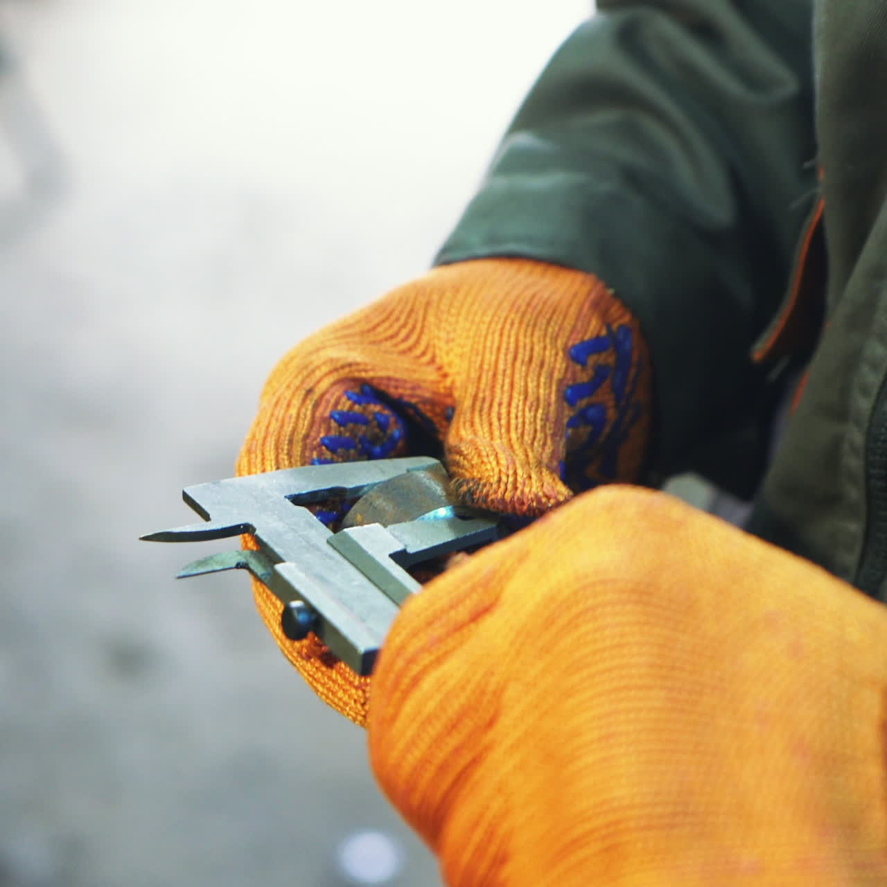 Industrial worker is working on metal work factory process by performing mechanical turning operation at machine for steel structure industry. Hands close up.