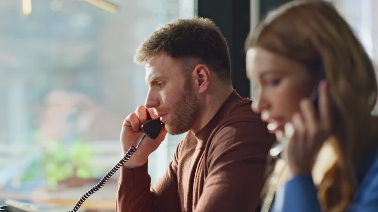 Call center workers talking telephone in office closeup. Two support employees