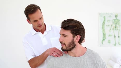 Physiotherapist-checking-patients-injured-shoulder-while-talking