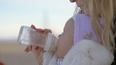 Mother-feeding-her-baby-girl-outside