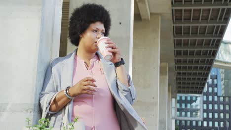 mujer biracial de talla plus bebiendo café en la ciudad
