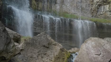 water cascades over a rocky ledge surrounded by boulders in a peaceful natural setting