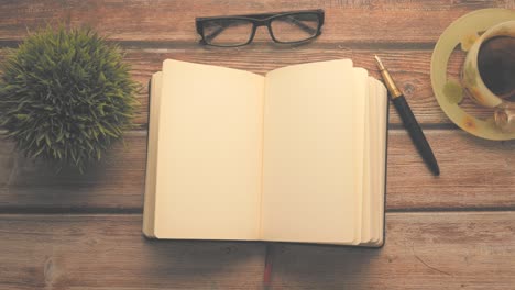 open notebook, glasses, pen, and tea cup on wooden desk