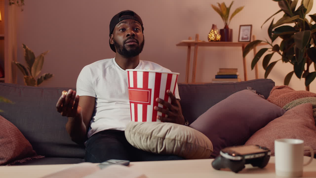 Man watching tv and eating popcorn on the couch