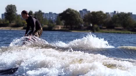 sporty man wakeboarding on river. young sportsman wake surfing on waves