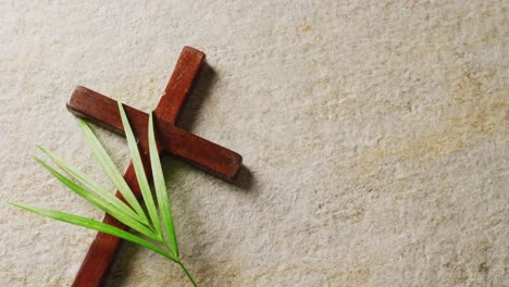 Close-up-of-palm-tree-leaves-and-cross-on-white-background-with-copy-space