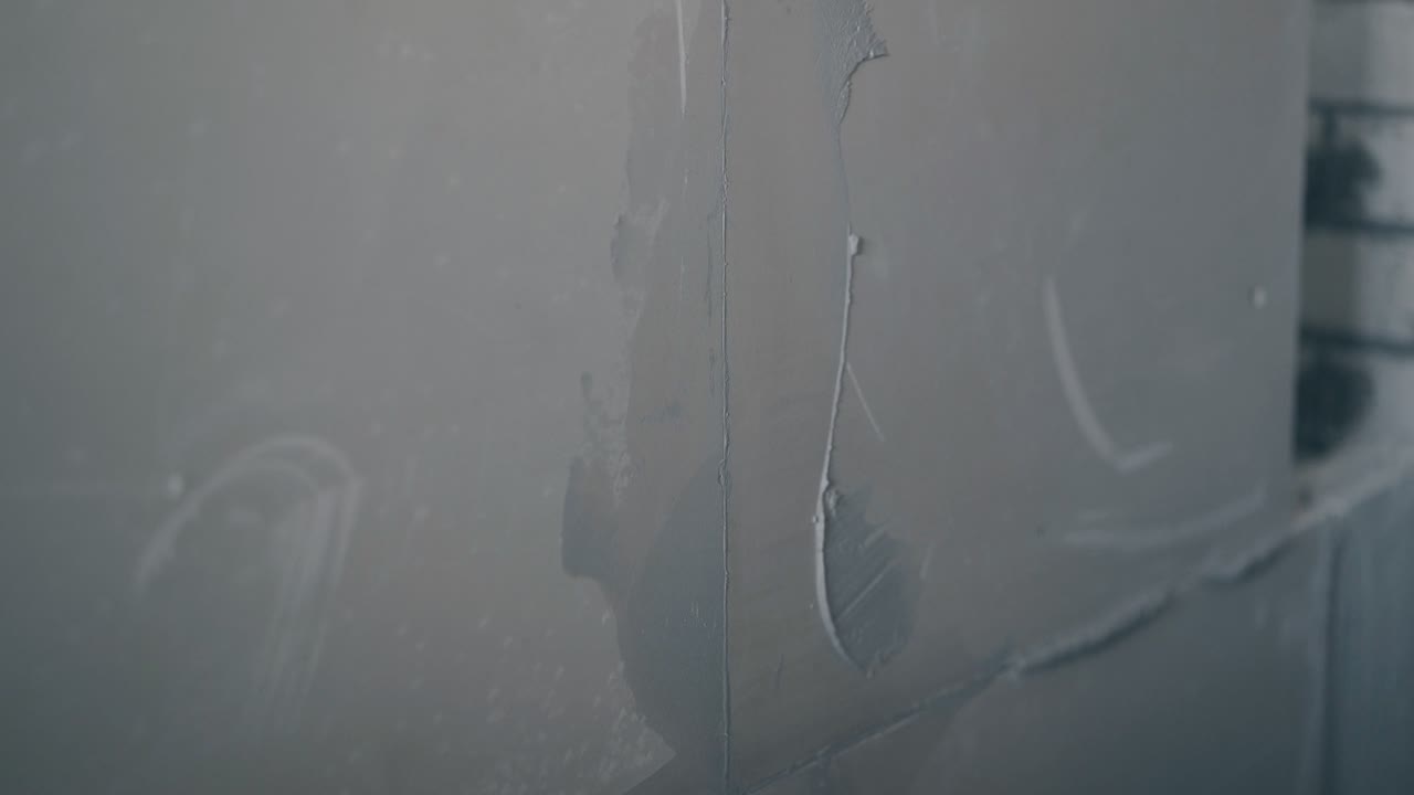 painter arm holds putty knife and smears wall with primer