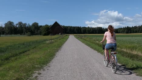 Mujer-En-Bicicleta-Por-Carretera-Rural-En-El-Campo-En-Verano