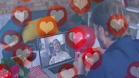 iconos del corazón flotando sobre el hombre caucásico mostrando un anillo mientras tiene una videollamada en la computadora portátil