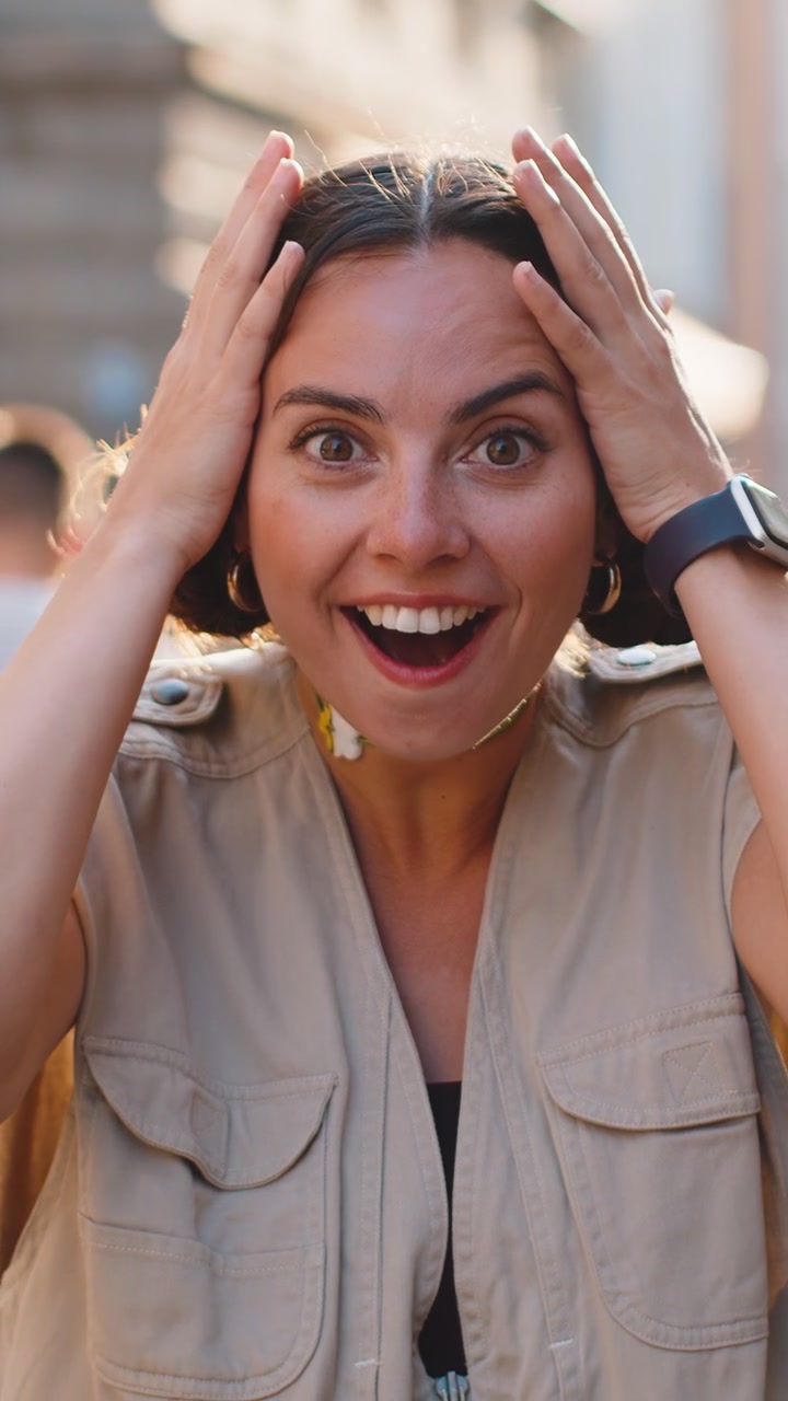 Giovane donna guardando sorpreso alla telecamera scioccato da improvvisa vittoria buona notizia vittoria wow in strada della città
