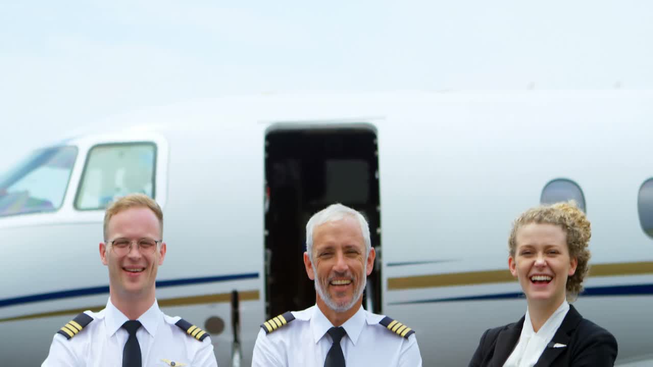 Two male pilots and flight attendant standing with arms crossed on a runway 4k