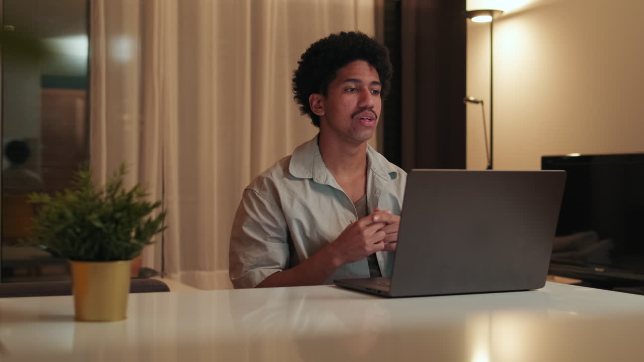 Young Man Talking and Gesturing During Video Call on Laptop at Home
