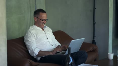 hombre de negocios sonriente trabajando en una computadora portátil en la oficina de casa. hombre profesional escribiendo en el teclado de la computadora portátil en el lugar de trabajo de la oficina
