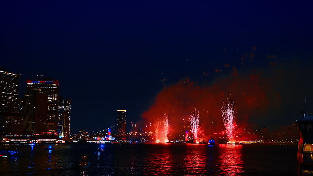 Variegated flashes of stunning fireworks over the river at night. Holiday celebration in beautiful New York, USA. View from the riverscape