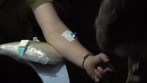a military doctor secures an intravenous access device with surgical tape to a ukrainian soldier suffering concussion at a frontline stabilisation point field hospital at an undisclosed location.