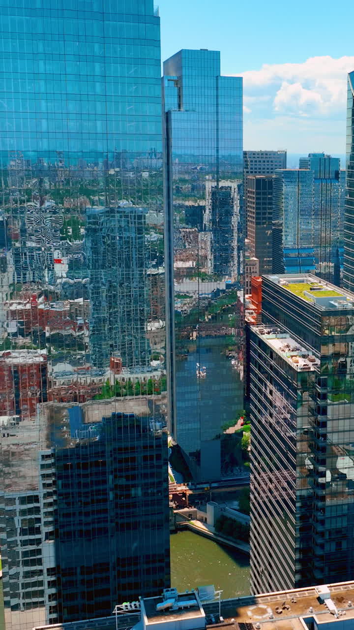 Rascacielos de cristal con ventanas espejadas en el centro de Chicago. Vista aérea de las calles de la ciudad y el río. Vídeo vertical
