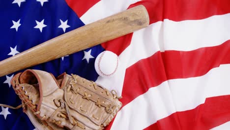 béisbol, bate de béisbol y guantes de béisbol en una bandera estadounidense