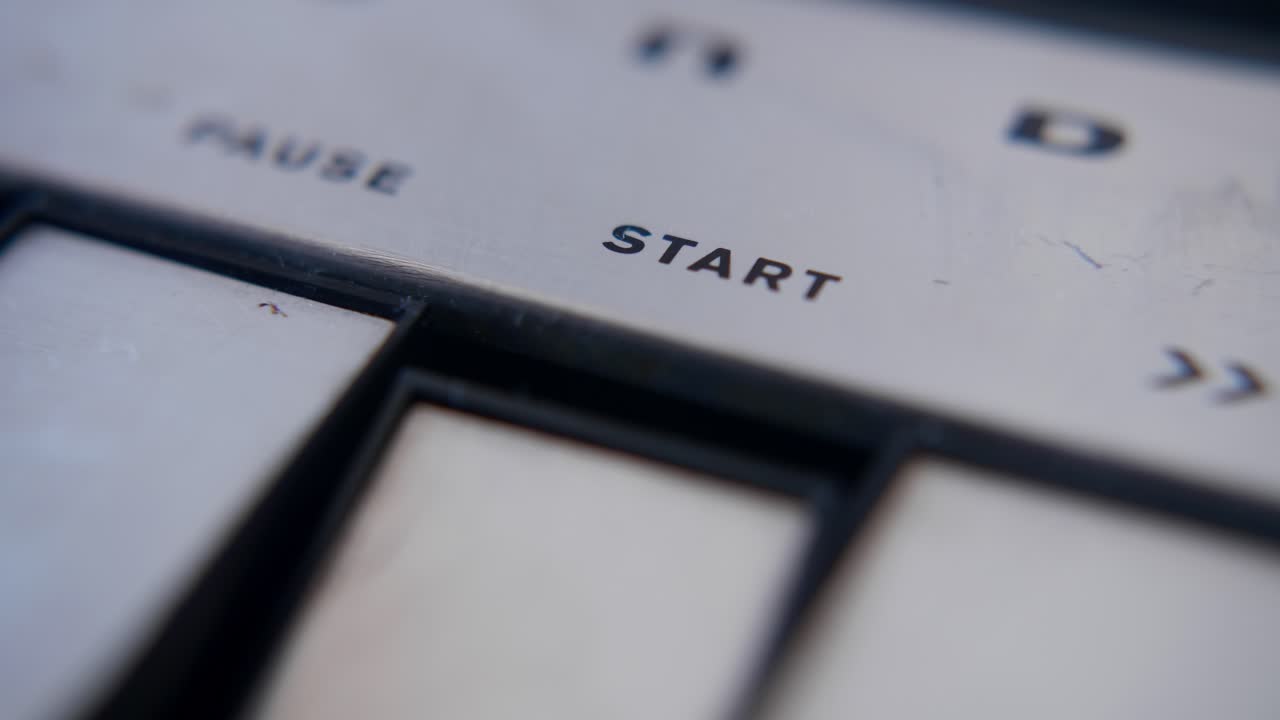 Close-up of Finger Pressing Start Button on Vintage Device