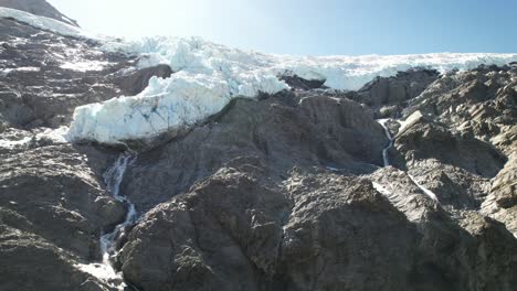 primer plano aéreo de un glaciar colgado de la cima de la montaña derritiéndose en cascadas
