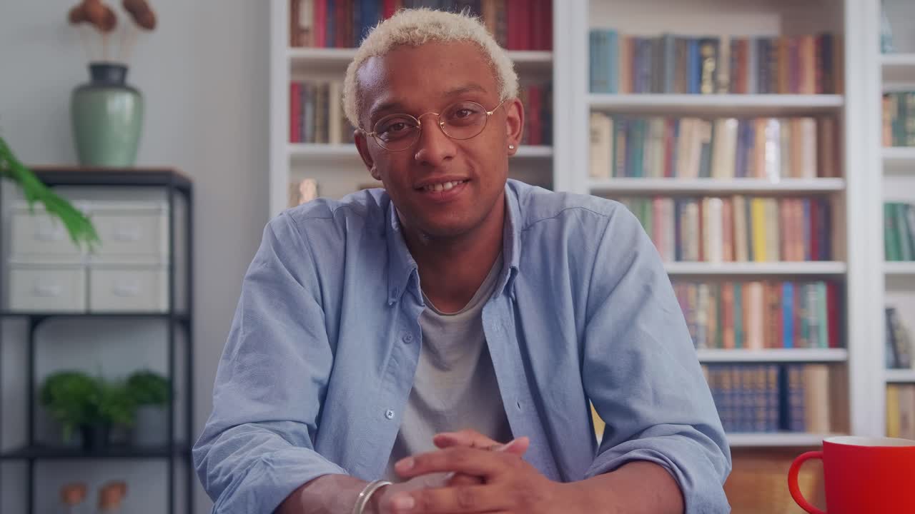 Bell'uomo afroamericano sorride in modo affascinante alla scrivania nel soggiorno.