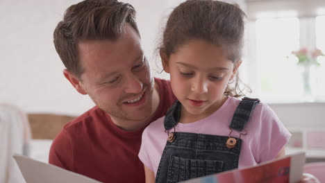 father and daughter in bedroom reading book together