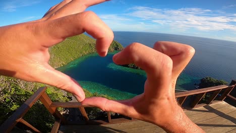 punto de vista de un hombre mirando una laguna en forma de corazón y formando un corazón con sus manos