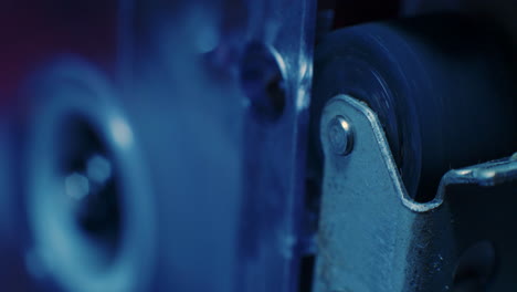 Extreme-Close-Up-Of-Pinch-Roller-Of-Microcassette-Recorder-With-Cassette-Reel-Rotating-in-Background-With-Cold-Blue-Lighting